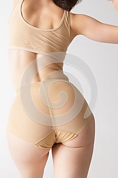 Sportive female body, buttocks in panties, underwear  over gray studio background. Concept of fitness, diet