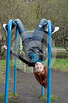 Sportive girl hanging on horizontal bar