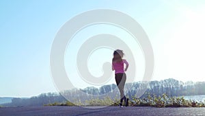 Sportive girl jogging along the river bank during sunrise or sunset. healthy lifestyle concept of athletic woman goes in