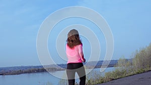 Sportive girl jogging along the river bank during sunrise or sunset. healthy lifestyle concept of athletic woman goes in