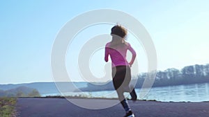 Sportive girl jogging along the river bank during sunrise or sunset. healthy lifestyle concept of athletic woman goes in