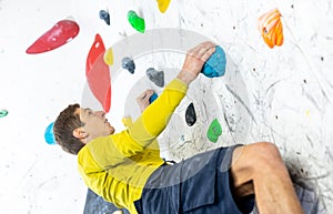 Sportive man climbing the boulder wall in a climbing centre, sport activity concept