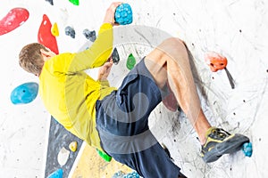 Sportive man climbing the boulder wall in a climbing centre, sport activity concept