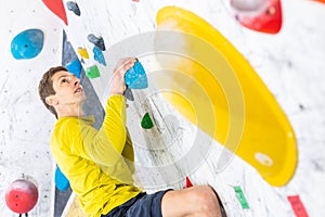 Sportive man climbing the boulder wall in a climbing centre, sport activity concept