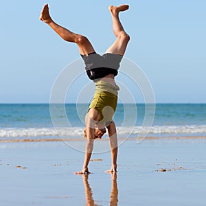 Sportive man doing gymnastics on the beach