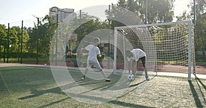 Sportive man playing football with preteen boy