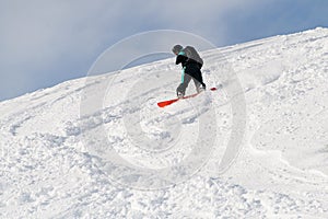 sportive man on snowboarder riding freeride on powder snow down the slope