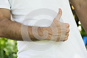 Sportive man thumbing up in white T-shirt