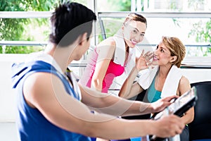 Sportive man on treadmill flirting with smiling girls