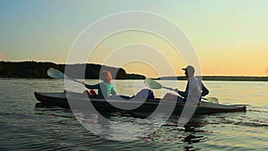 Sportive man and woman paddling boat synchronously, active rest