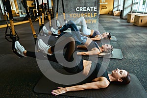 Sportive people . Three young athletic women exercising with trx fitness straps at gym, working out together