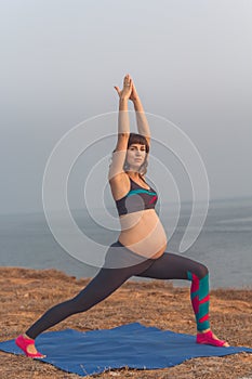 Sportive pregnant girl doing yoga outdoors