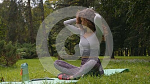 Sportive slim woman outdoors in park stretch neck muscles lower head down stretching back warm up before fitness