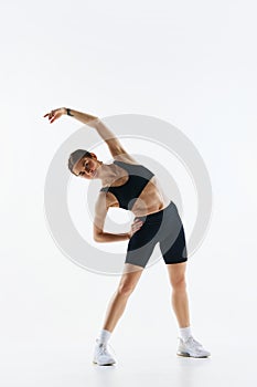 Sportive, sling young woman with with body, in sportswear training, doing stretching exercises isolated over white