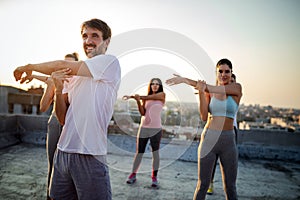 Group of athletic young people, friends in sportswear doing exercises. Sport outdoors