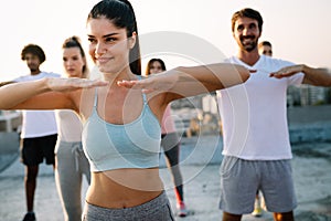 Group of athletic young people, friends in sportswear doing exercises. Sport outdoors