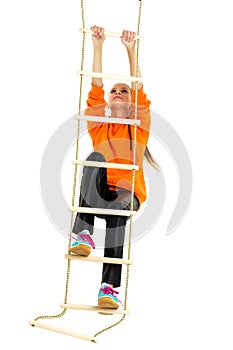 Sportive teen girl playing on rope ladder