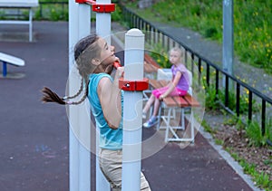 Sportive teenage girl making pull ups on the horizontal bar on a playground