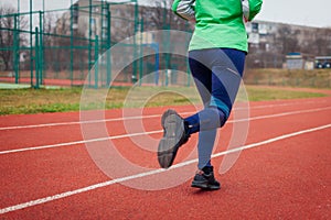 Sportive woman athlete running on sportsground in autumn. Close up of sneakers and legs. Active healthy lifestyle