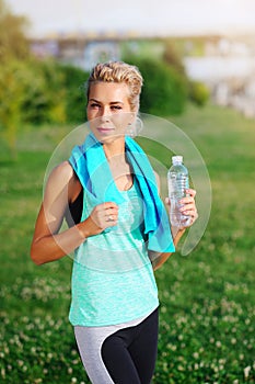Sportive woman drinking water after workout