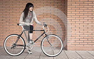 Sportive woman with fixie bike over a brick wall