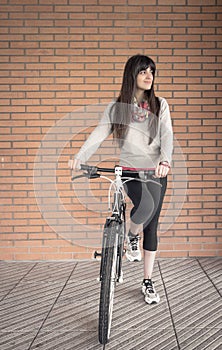 Sportive woman with fixie bike over a brick wall