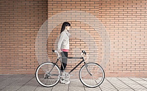 Sportive woman with fixie bike over a brick wall