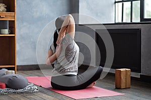 Sportive woman making yoga asana gomukhasana in siddhasana