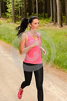 Sportive woman running through forest