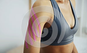 Sportive woman sits indoors with kinesio tape on her hand