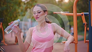 Sportive woman standing summer day on sport ground resting after hard training drink water plastic bottle medium shoot