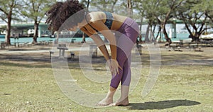 Sportive woman training yoga in park