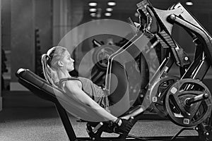 Sportive woman using weights press machine for legs. Gym.