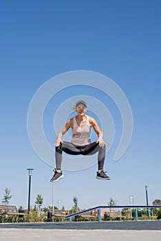 Sportive woman working out on the sports ground in sunny summer day