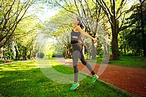 Sportive young fitness woman jumping in summer park