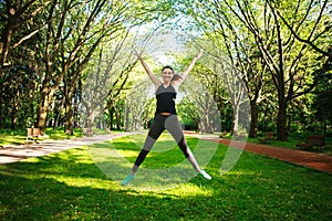 Sportive young fitness woman jumping in summer park