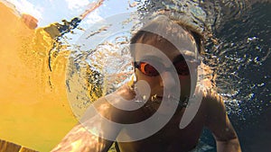 Sportive young guy in the swimming pool, underwater view. Vacation summer time. Action camera