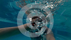 Sportive young man in orange glasses in the swimming pool. Vacation summer time. Action camera