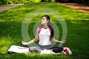 Sportive young woman relaxing in sunshine, doing yoga exercises