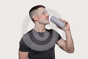 Sportman Drinking from Tin Can Drink. Energy Drink for Sport. Man with Can in Hands. photo