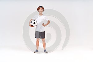 Sports activities. Full-length shot of a happy teenage boy holding soccer ball, looking at camera and smiling while