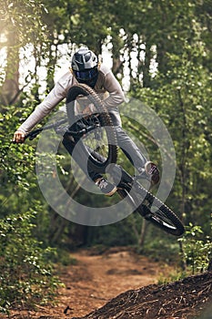 Sports, adventure and forest with man and mountain biking on park trail for action, freedom and fitness. Jump, speed and