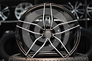 Sports alloy wheel rim with carbon cover, in the hall of the car shop on the background of wheels. Front view