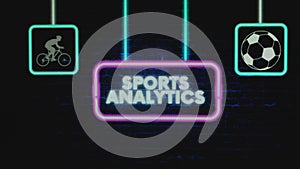 Sports Analytics appearing inscription in pink neon frame on brick wall background with sports symbols. Sports concept