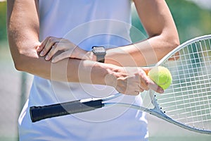 Sports, arm pain and tennis player with a racket and ball standing on a court during for a match. Closeup of a health