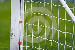 Sports Background; Net of Soccer Goal. Blurred Green Field Pitch in the Background