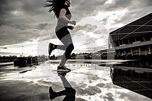 Sports background. Strong athletic legs of a woman runner in motion. Morning workouts outdoors after the rain