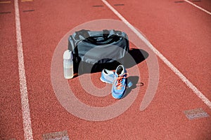 Sports bag, shoes and a water bottle kept on a running track