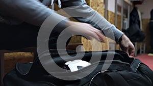 Sports bag with sports equipment. The man's hands are unzipping a sports bag