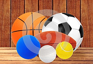 Sports balls on wooden table over wooden planks background